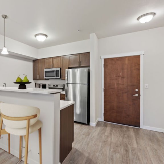 a kitchen with a bar stool and a refrigerator.