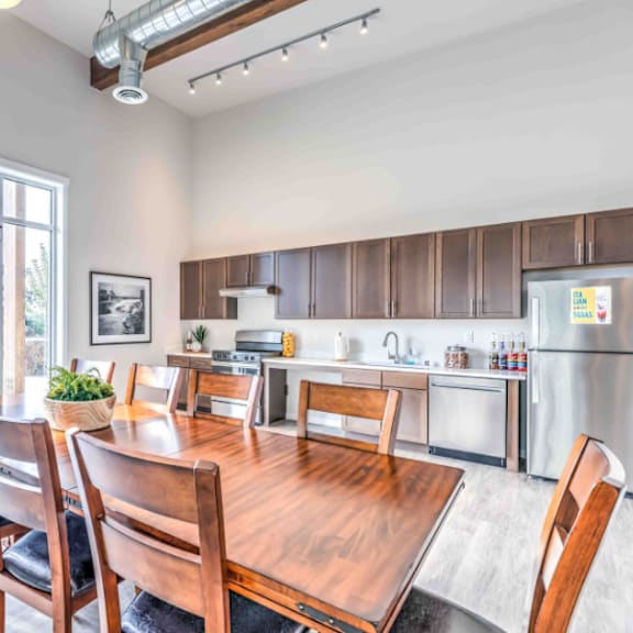 a dining room with a wooden table and chairs, a fridge, and a window with a view of the outdoors.