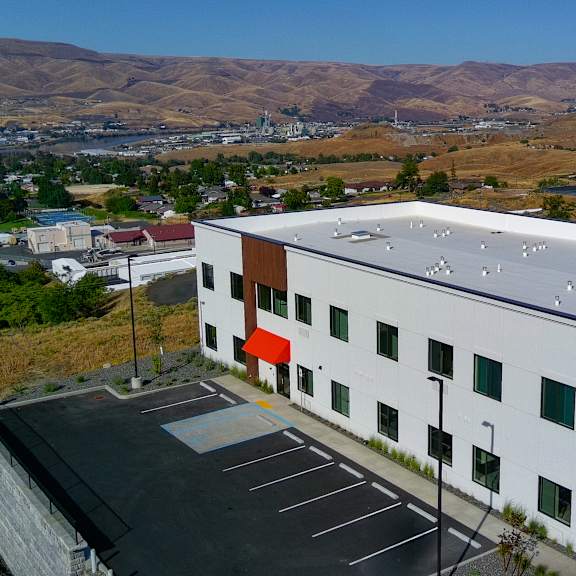 a white building with a red awning is surrounded by a parking lot.