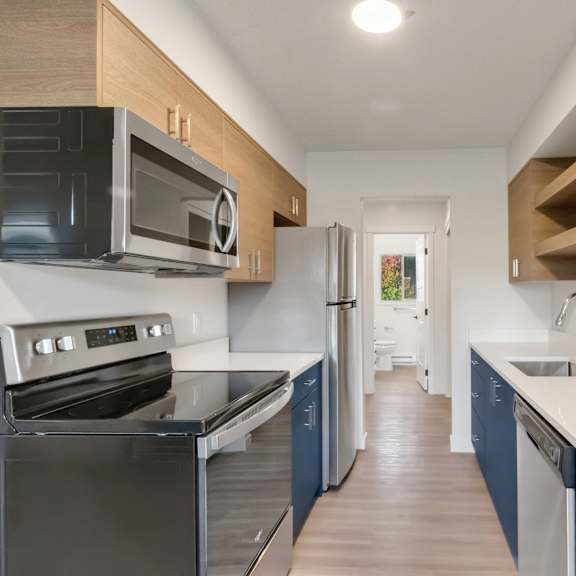 a kitchen with blue cabinets and stainless steel appliances and a white counter top