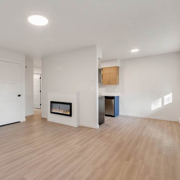 a living room with a fireplace and a door into a kitchen