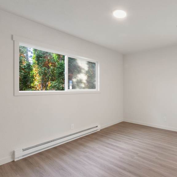 an empty room with white walls and a large window