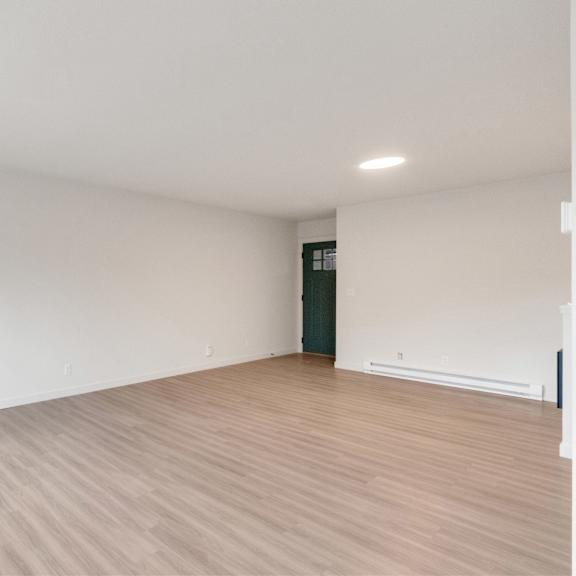 an empty living room with white walls and wood flooring