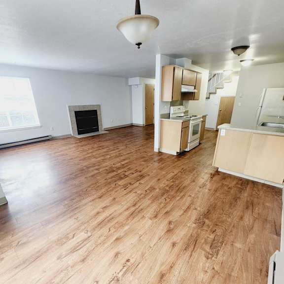 an empty living room and kitchen with wood flooring