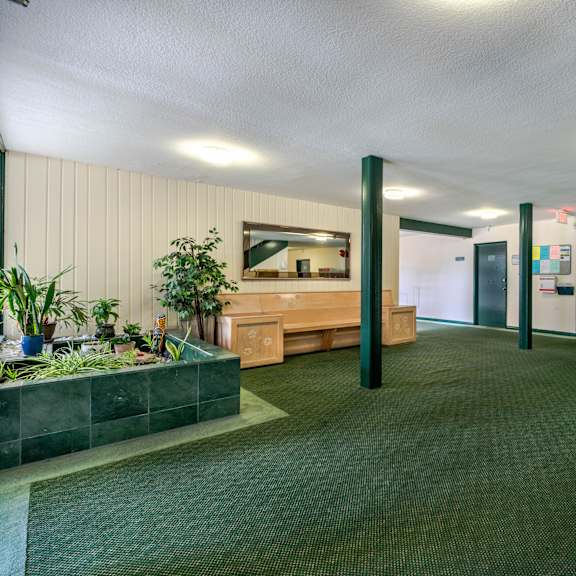 a room with a bench, a planter, and a bulletin board on the wall.