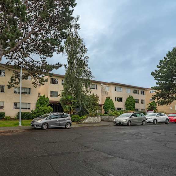 a parking lot with cars and a building in the background.