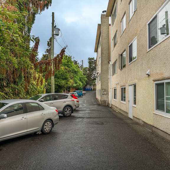 a street with parked cars and apartment buildings on both sides.