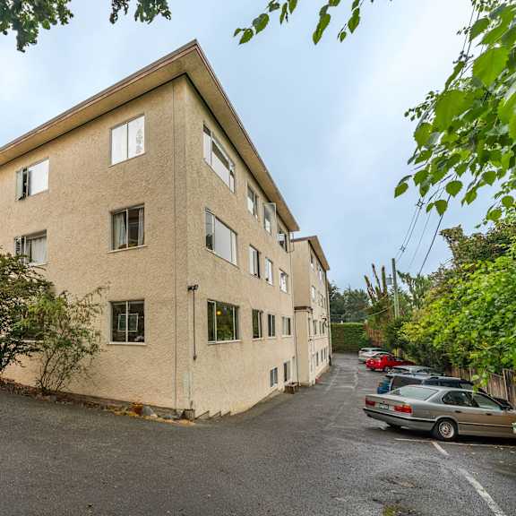 a beige building with a parking lot in front.