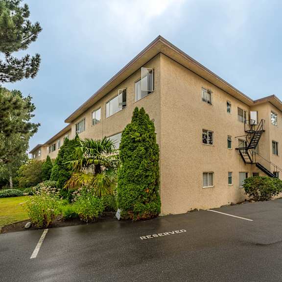 a beige building with a parking lot in front.