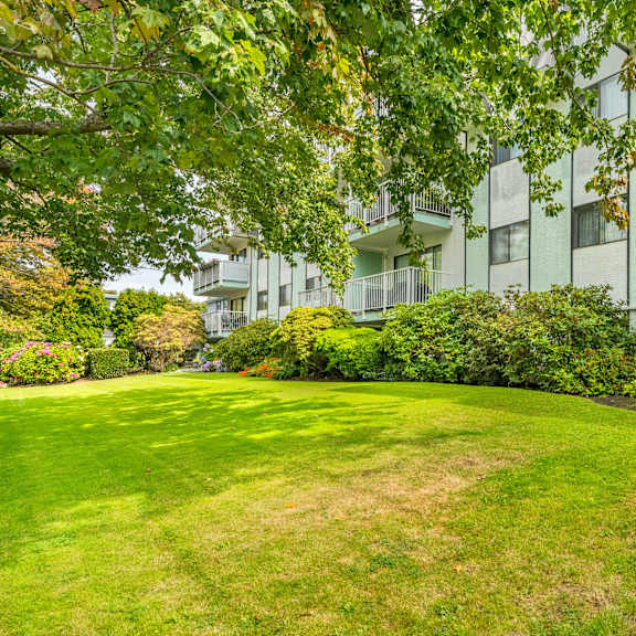 a green lawn in front of a white building with balconies.