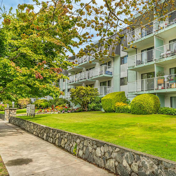 a building with a balcony and a green lawn in front.