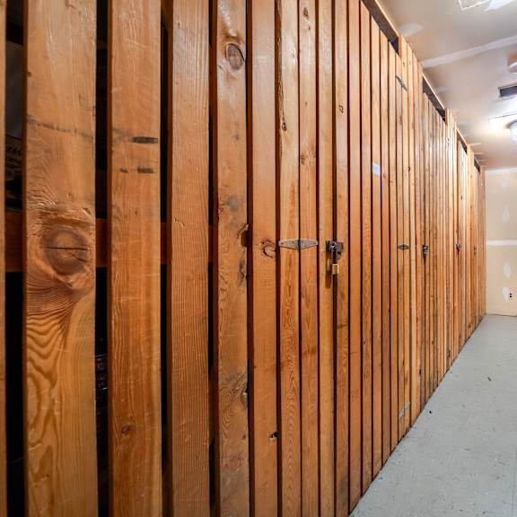 a long hallway with wooden walls and doors on both sides.