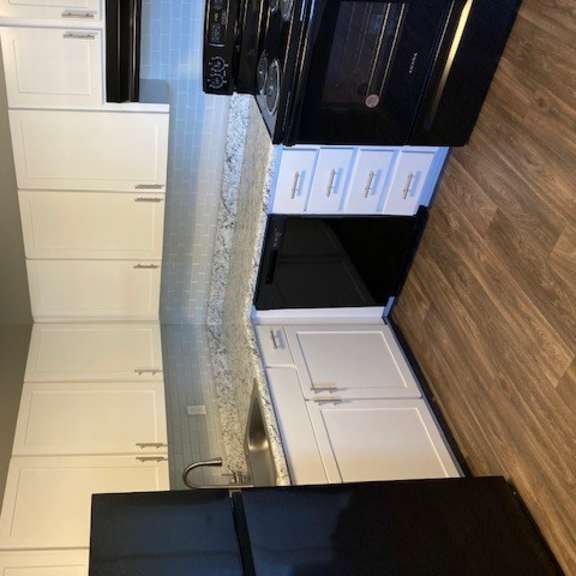 a kitchen with white cabinets and black appliances