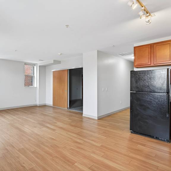 a black fridge sits in a room with wooden floors and white walls.
