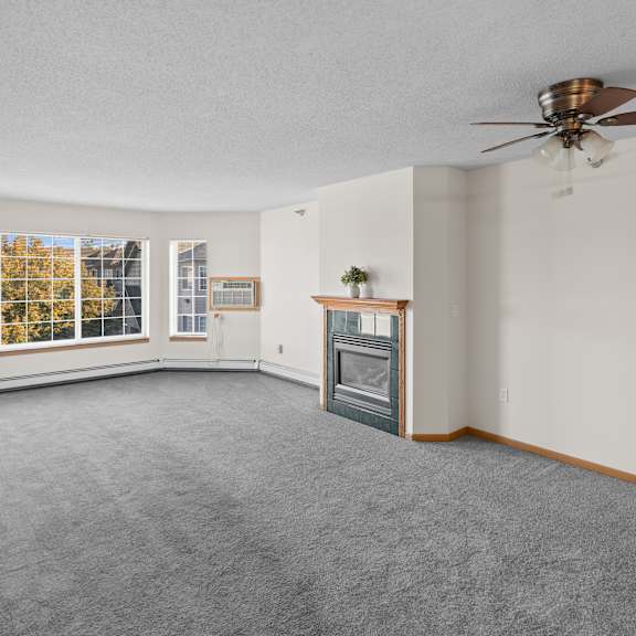 a spacious living room with a fireplace and a ceiling fan.