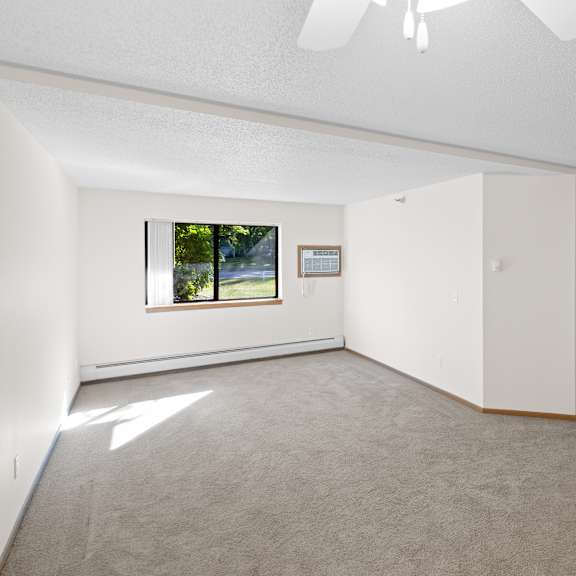a room with a ceiling fan and a window with a view of trees.