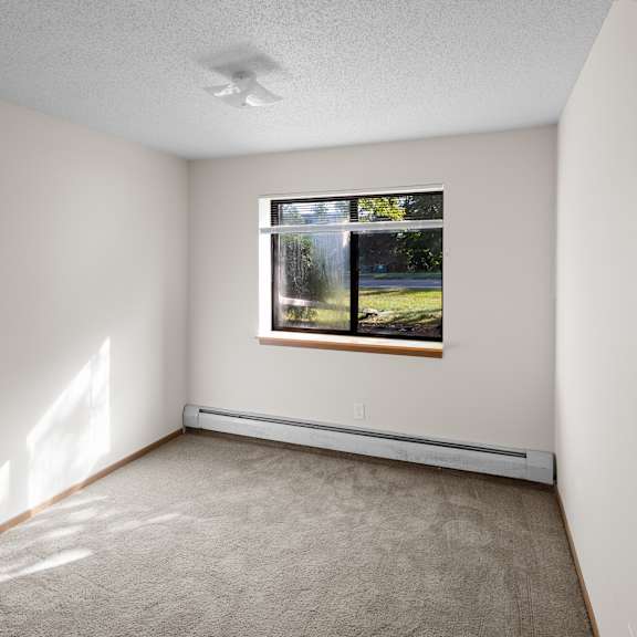 a room with a window showing a view of trees and a house.
