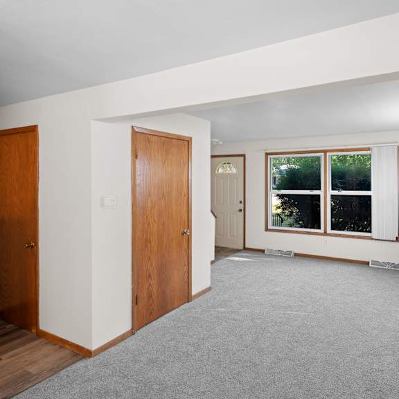 a room with a grey carpet and wooden doors.