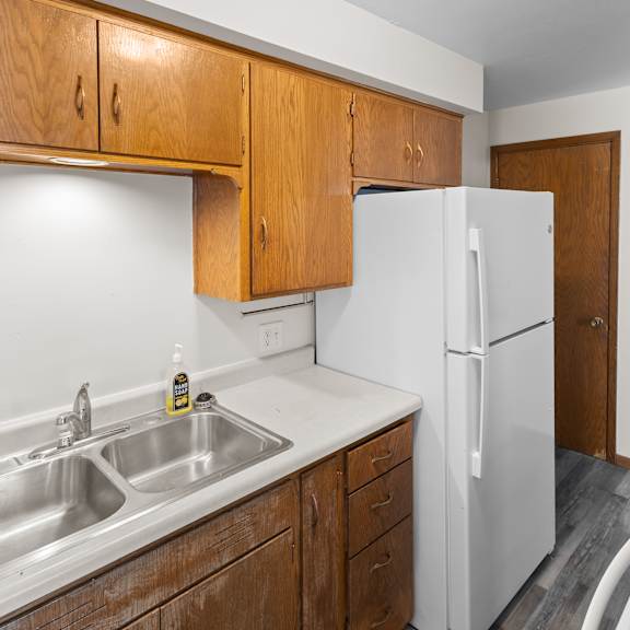 a kitchen with a white fridge and wooden cabinets.