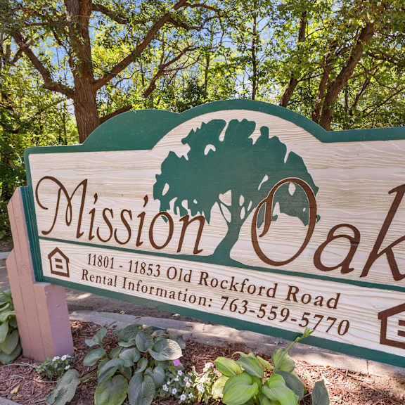 a sign for mission oaks with a tree logo and a phone number.