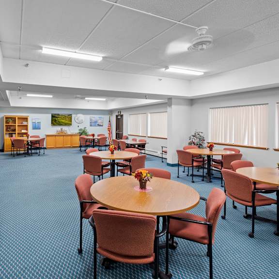 a room with tables and chairs and a blue carpet.