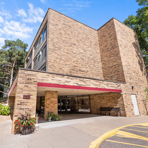 a building with a red awning and a sign that reads "the pine tree" is surrounded by trees and plants.