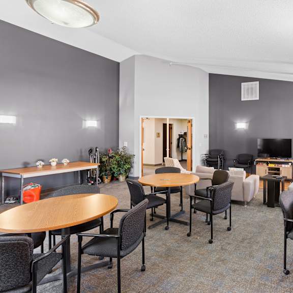 a room with grey walls and a carpeted floor has a table and chairs in it.