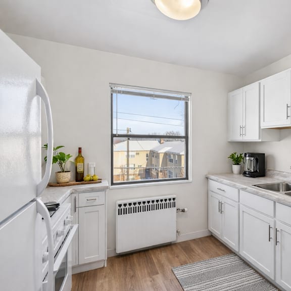 a kitchen with white cabinets and a window overlooking buildings.