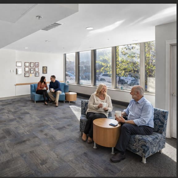 a group of people are sitting in a room with a large window.