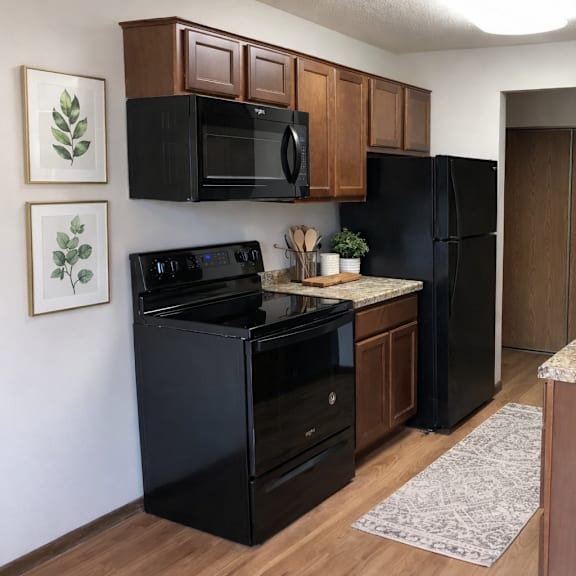 a black oven and microwave in a kitchen with brown cabinets.