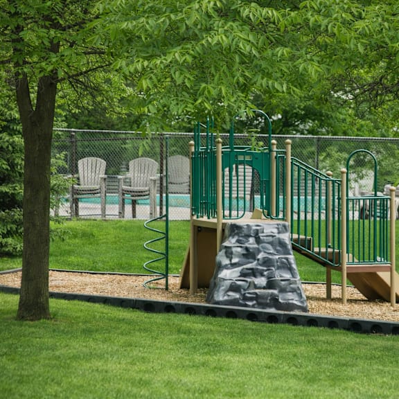a playground with a green slide and a brown rock-like structure.