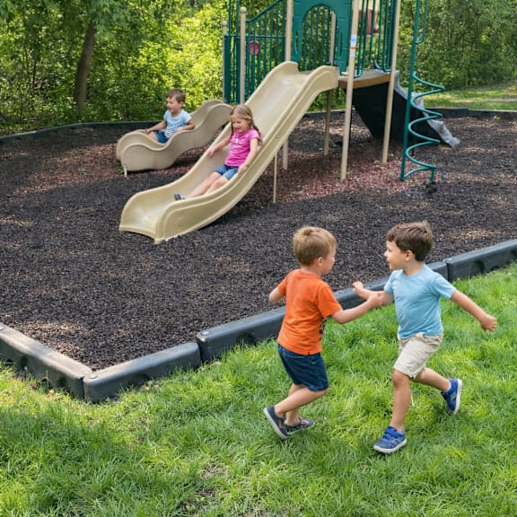 two young boys are playing on a slide in a playground.