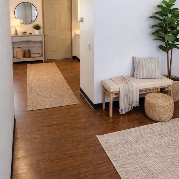 a room with a wooden floor and a white wall with a mirror and a door.