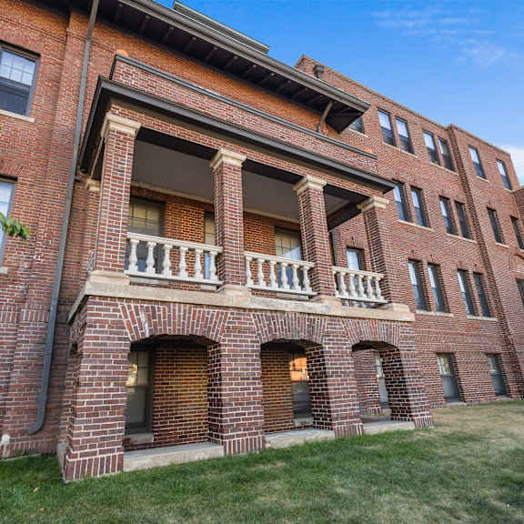 a red brick building with a balcony in the middle.