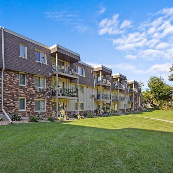 a large, multi-story residential building with a mix of stone and siding exterior.