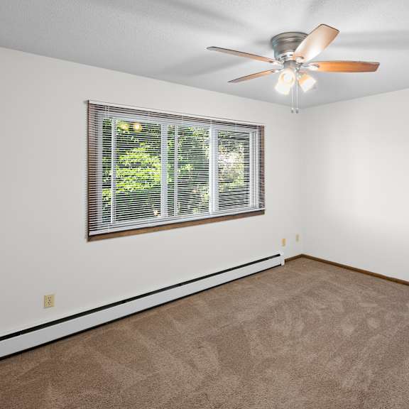 a room with a ceiling fan and a window with blinds.