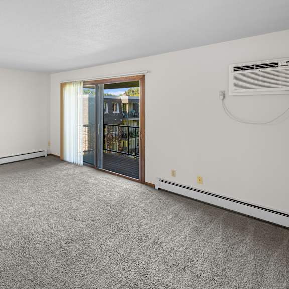 a room with a grey carpet and a sliding glass door.
