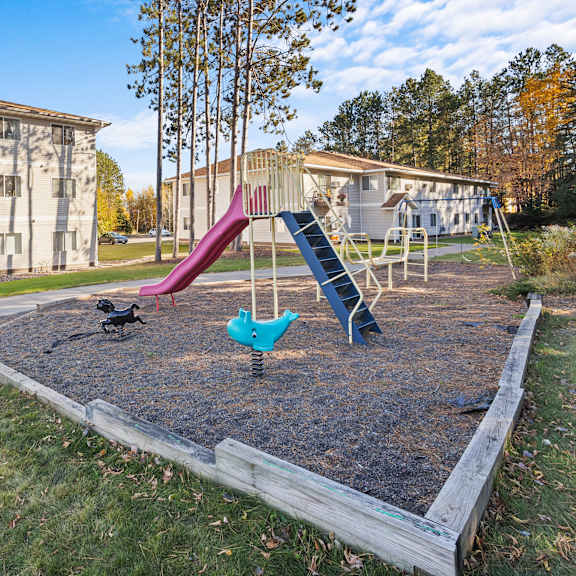 a playground with a slide and swings in a grassy area.