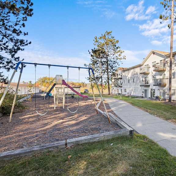 a playground with a swing set and a building in the background.