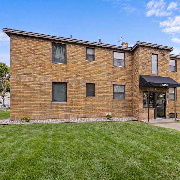 a brick building with a black awning and a sign that reads "411" is surrounded by a grassy lawn.