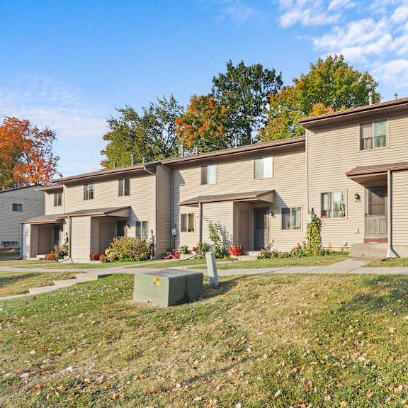 a row of houses with a grassy front yard.