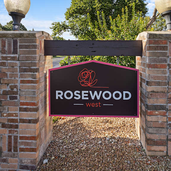 a sign that says rosewood west is displayed on a brick wall.
