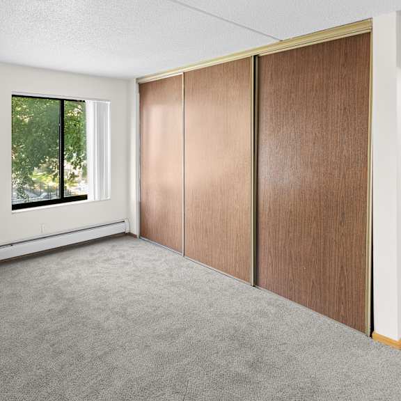 a room with a window and a brown wardrobe.
