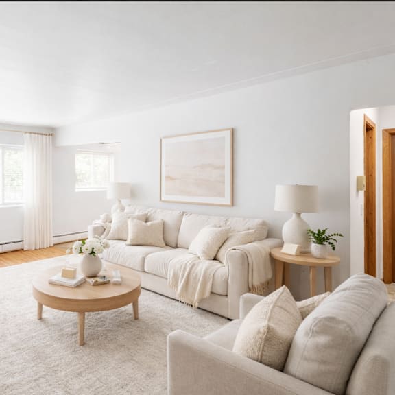 a living room with a white couch, a coffee table, and a painting on the wall.