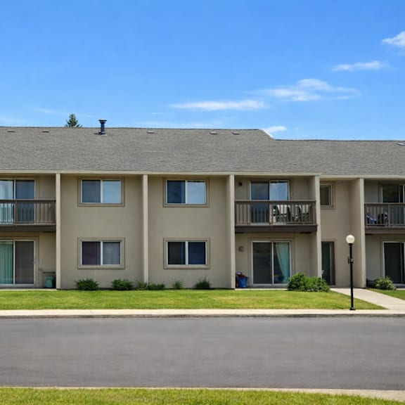 a large apartment building with a parking lot in front.