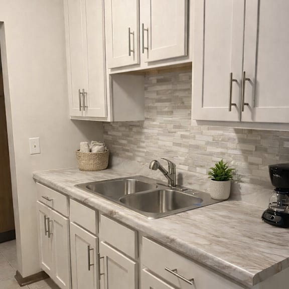 a kitchen with white cabinets and a marble countertop.