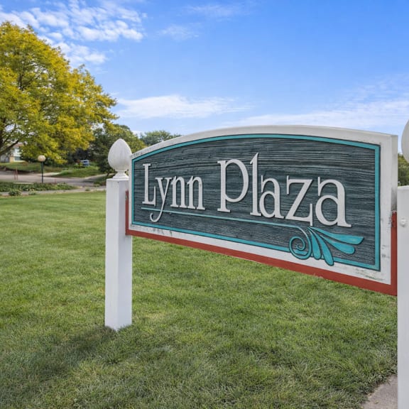 a sign that says lynn plaza stands in a grassy area.
