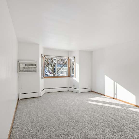 a large empty room with a window and a carpet on the floor.