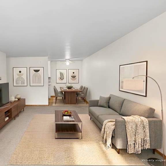 a living room with a grey couch, a coffee table, a bookshelf, and a lamp.