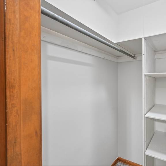 a white closet with shelves and a door.